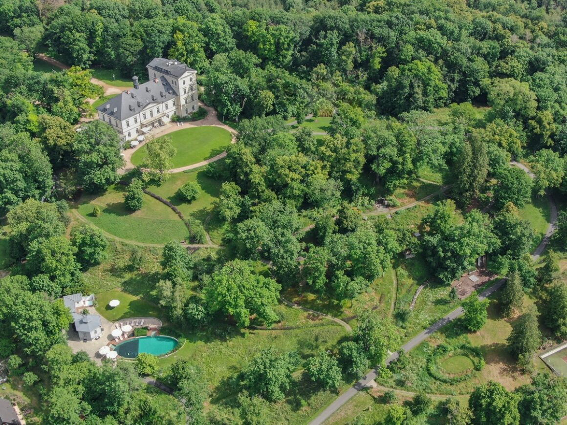 A castle lies in the middle of green fields and lush trees, a popular Czech Republic wedding venue