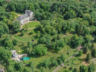 A castle lies in the middle of green fields and lush trees, a popular Czech Republic wedding venue