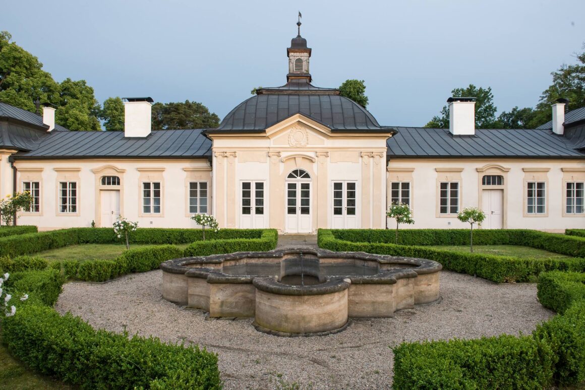 A white castle with dark blue roof with a stone fountain up front make up Zamek Bon Repos, a popular Czech Republic wedding venue