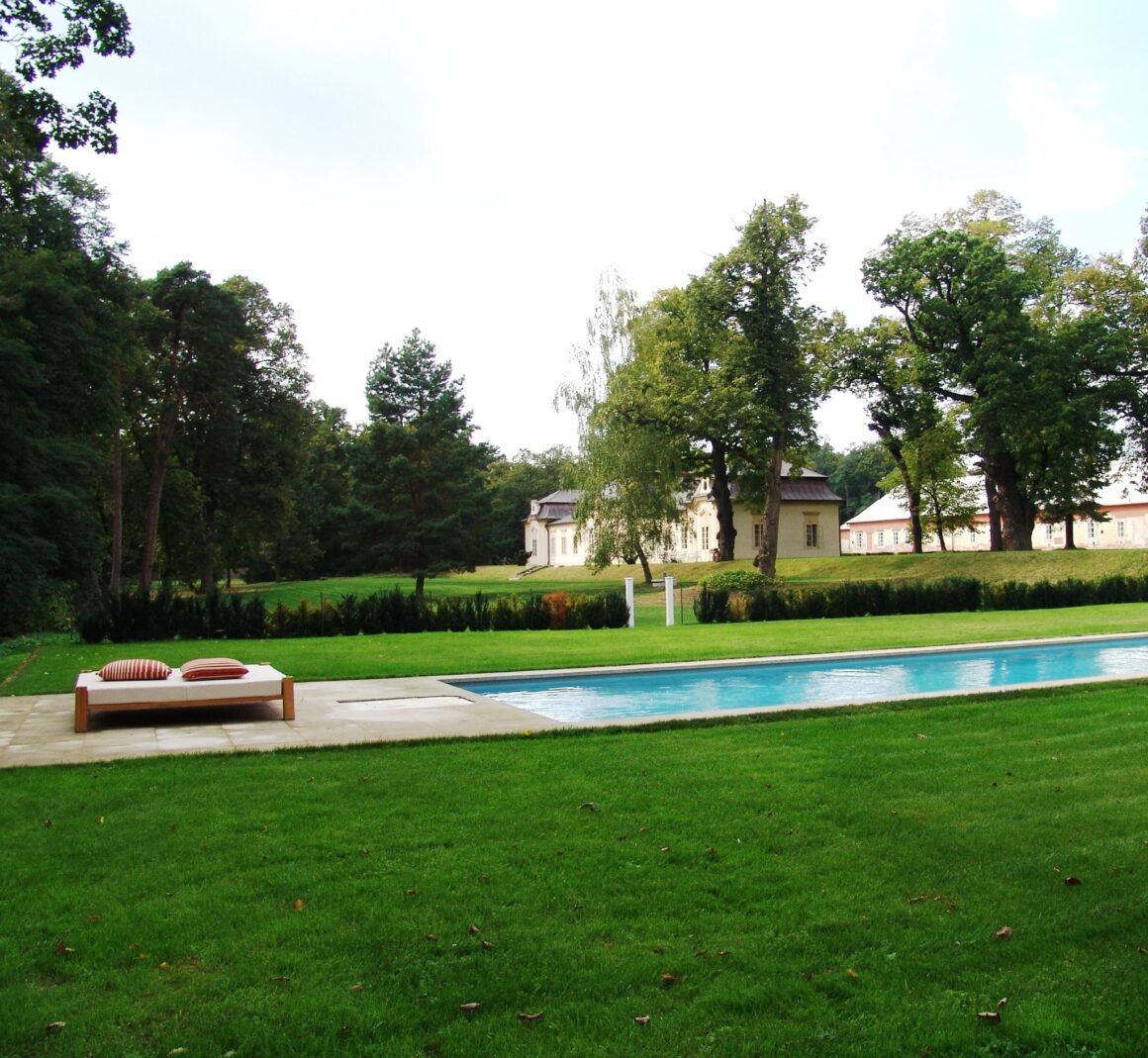 A pool is surrounded by green grass in the gardens of Zamek Bon Repos, a popular Czech Republic wedding venue