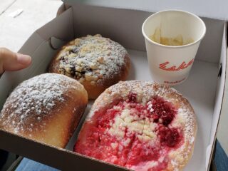 Kolac and buchty, two Czech baked goods featuring fresh fruit in yeasted dough, in a take out box alongside a small cup of espresso.