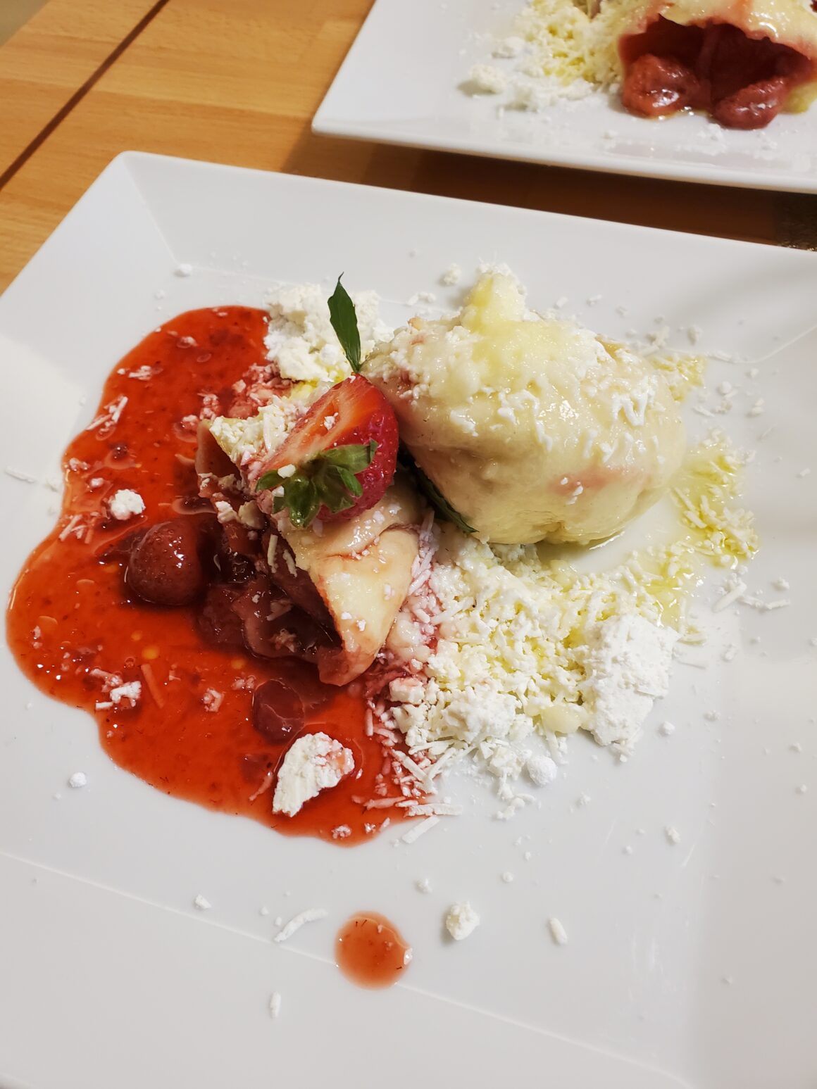 Dumplings stuffed with fruit are covered in a strawberry sauce, farmers cheese and powder sugar