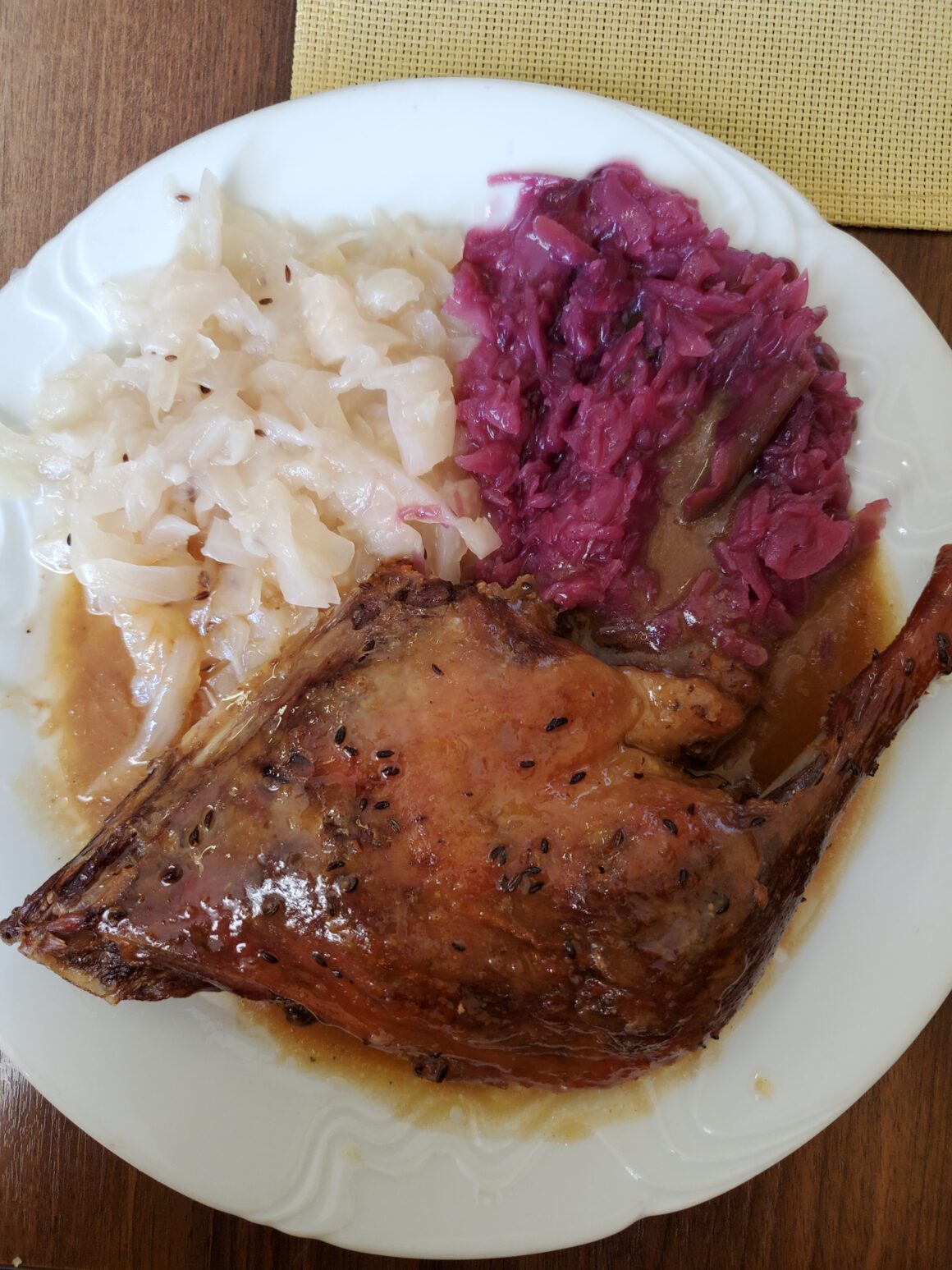 A roast duck is paired with white and red cabbage in a traditional Czech dish