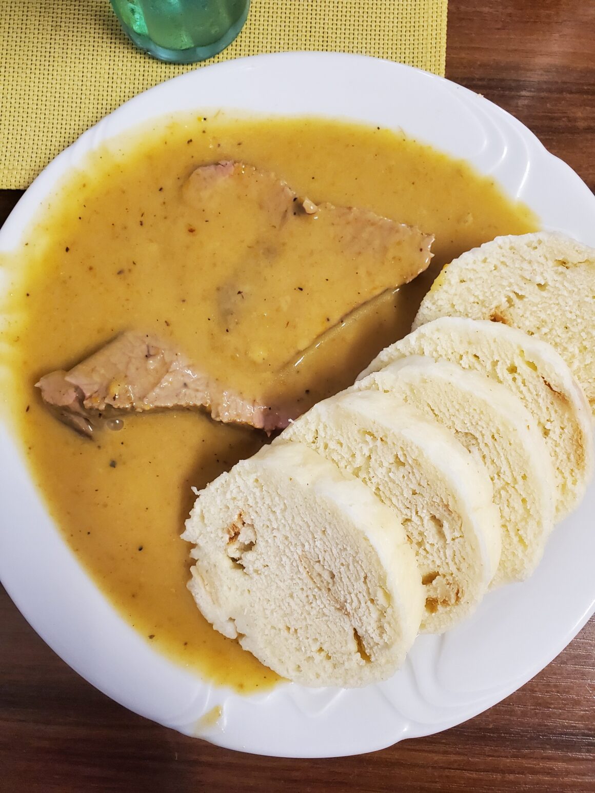 Bread dumplings are plated with a vegetable cream sauce and slow cooked beef sirloin in a traditional Czech dish