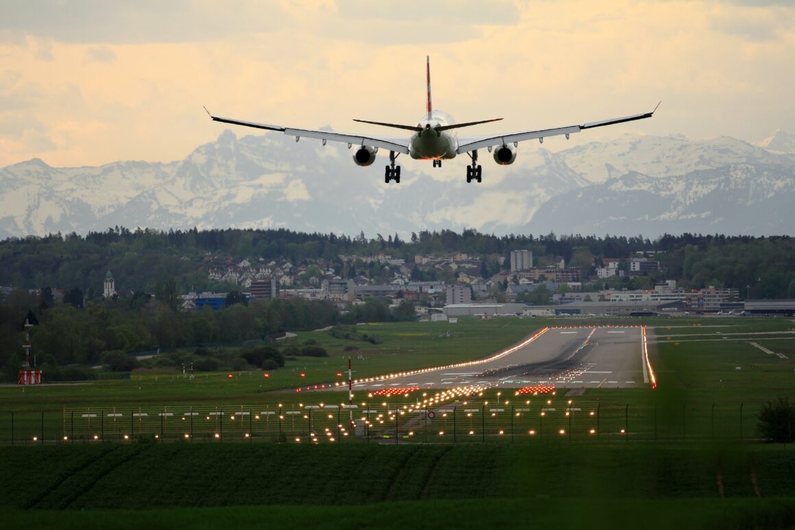 A plane lands on a runway in Denver with mountains in the backdrop