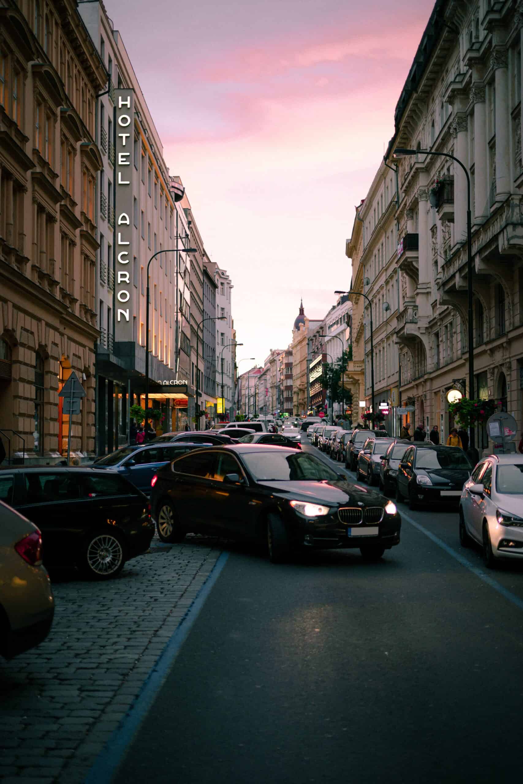 The sun sets between the colorful homes on a Prague street