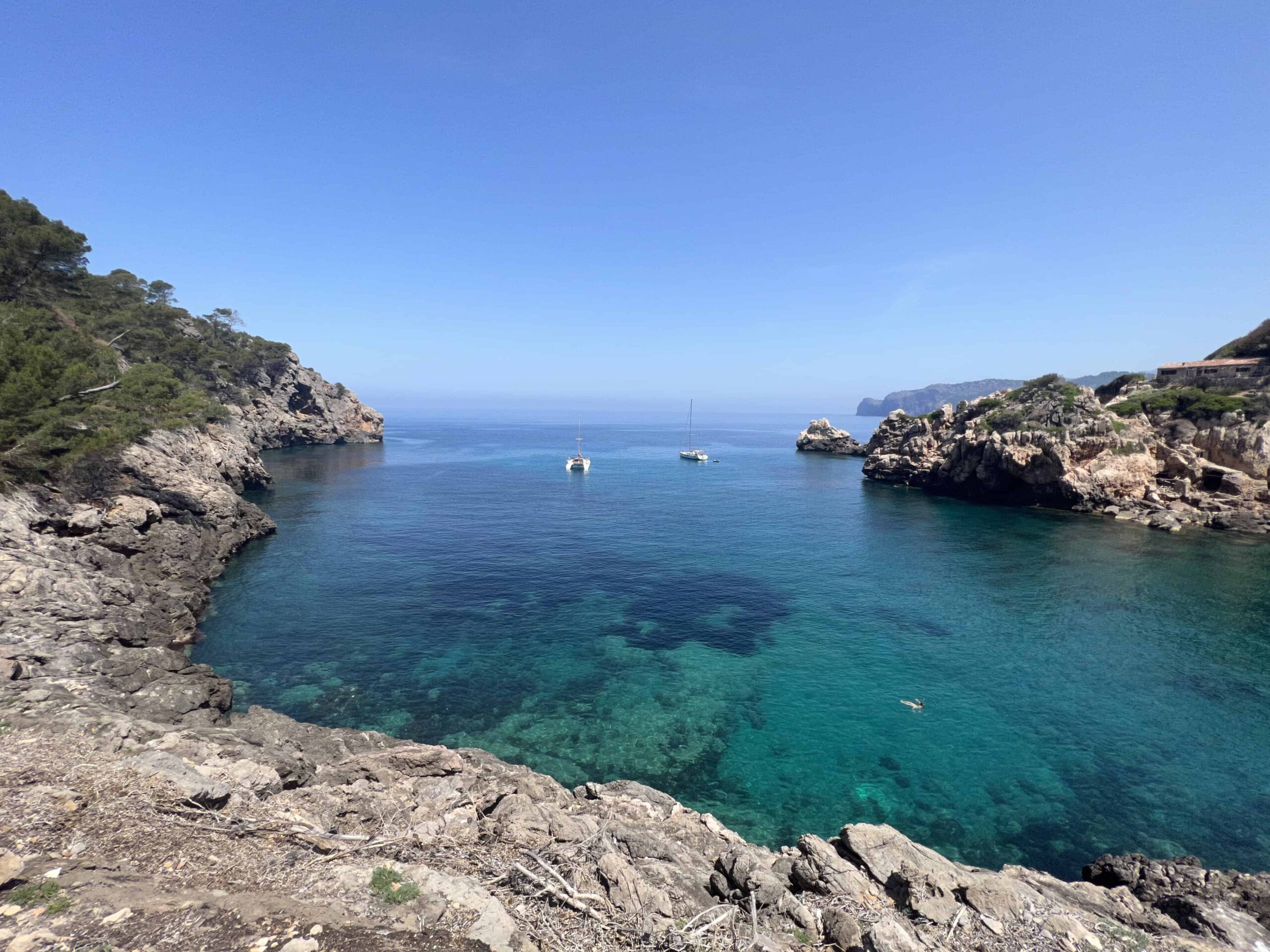 The bay of Caia Deia, one boat floating in the blue water, , one of the most beautiful beaches in Mallorca.