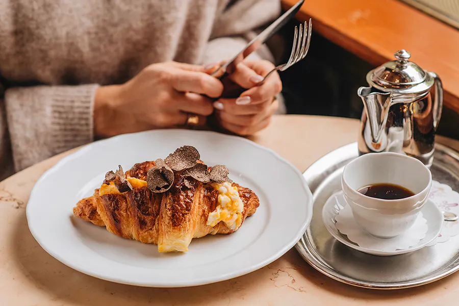 A woman prepares to eat a pastry at Cafe Savoy, one of the best brunch spots in Prague