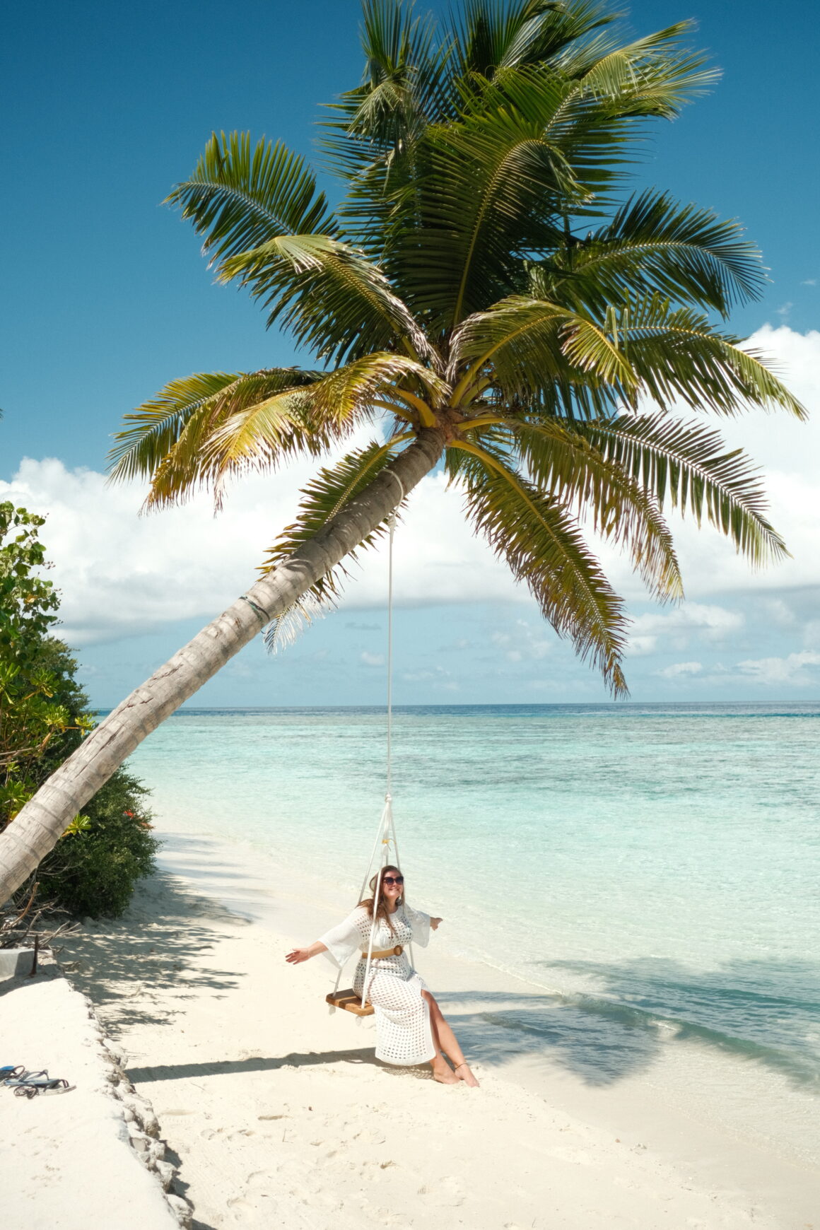 A smiling girl swinging on a swing in Thinadhoo, one of the most beautiful local islands in the Maldives