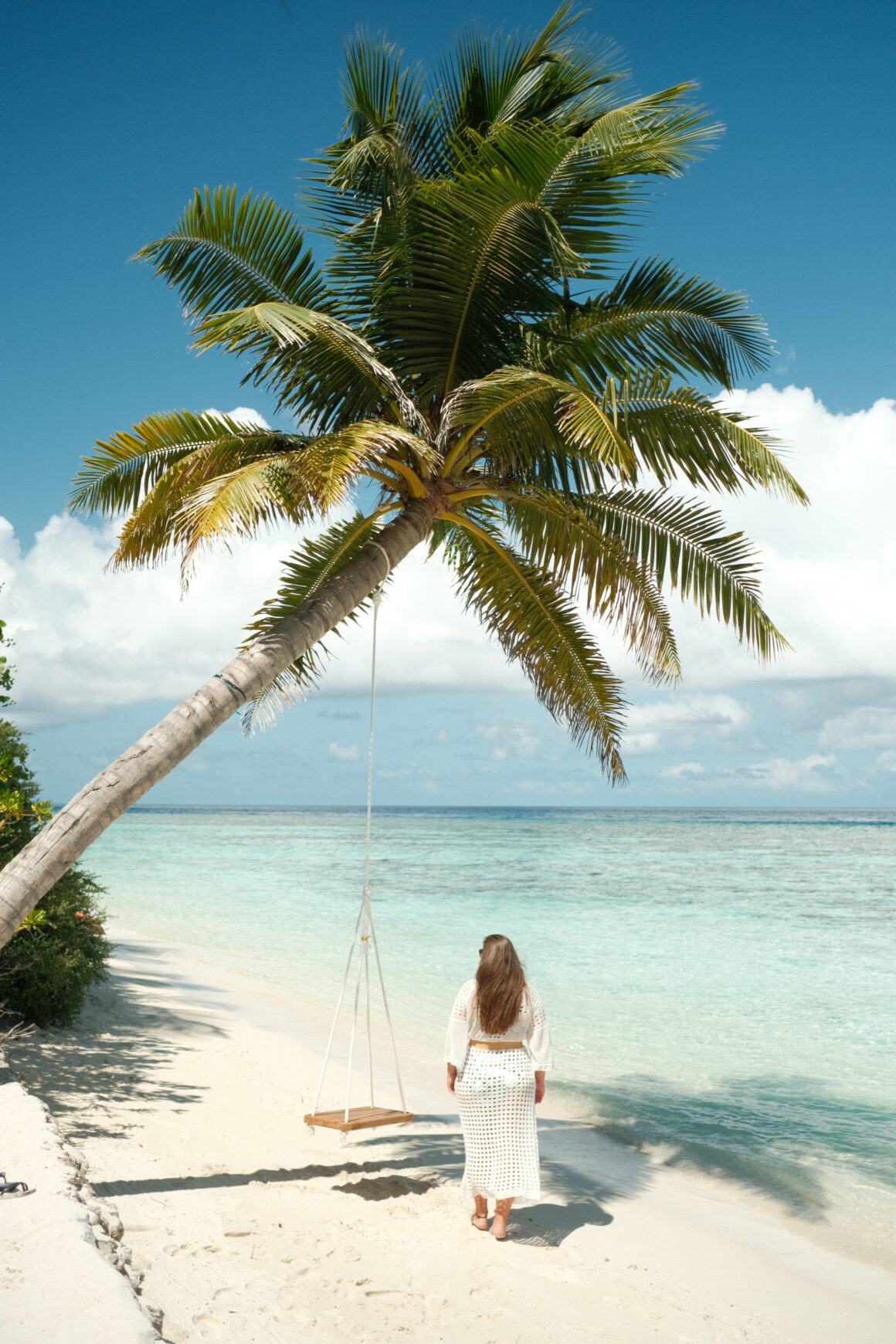 A smiling girl swinging on a swing in Thinadhoo, one of the most beautiful local islands in the Maldives