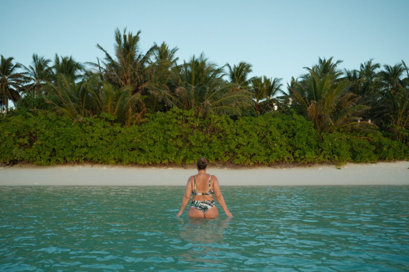 A girl walking in the water off one of the islands in the Maldives